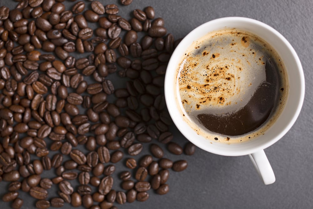 Still life of fresh roasted coffee beans with a white mug on a black slate surface-1